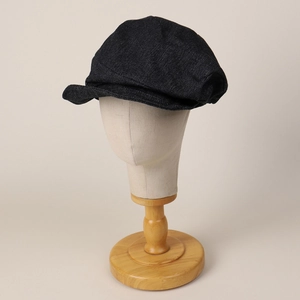 Japanese style dark denim newsboy cap with asymmetric pleats and soft brim on a model stand