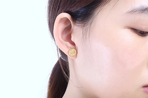 Gros plan d'un mannequin portant des boucles d'oreilles octogonales dorées à relief classique
