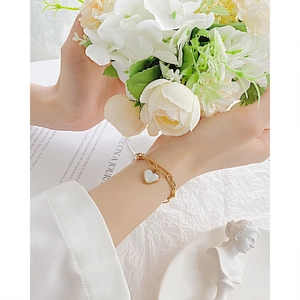 Double-layered gold pearl bracelet with heart pendant shown on model wrist