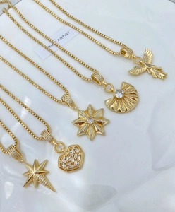 Detailed view of five gold-plated necklaces featuring star, heart, and winged pendants