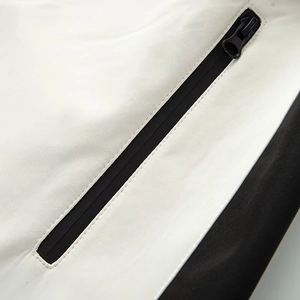 Macro view of white and black ski jumpsuit detail with zippered pocket and functional fabric
