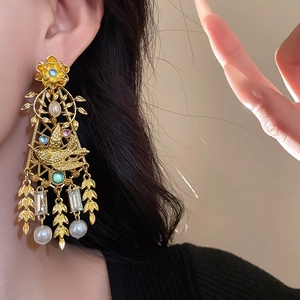 Detailed close-up of vintage flower and bird earrings with pearls and crystals