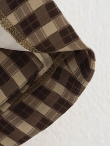 Dettaglio ravvicinato del tessuto a quadri marrone e beige con cuciture overlock