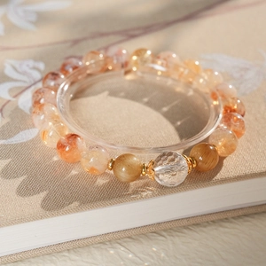 Detail of beaded crystal bracelet with translucent orange stones and faceted clear quartz