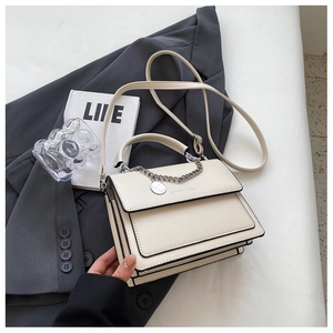 Detail of a creamy white PU leather handbag featuring a metal chain and a chic flip-top cover