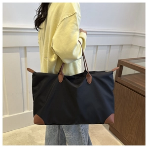 Close-up of black waterproof Oxford tote bag with brown leather handles and reinforced corners