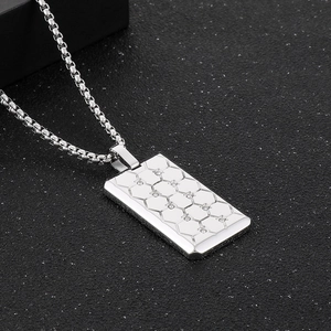 Détail macro du pendentif carré argenté avec motif alvéolé et diamants incrustés