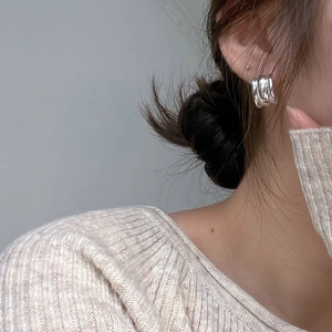 Close-up of minimalist silver hoop earrings with irregular textured surface on model