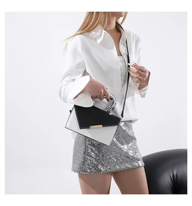 Detail of a chic black and white crossbody bag with a sleek silver metal top handle