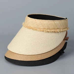 Detail view of woven straw sun visors in beige and brown with fringed lace edges