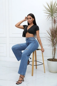 Detail of high waist blue straight denim jeans with distressed knee holes and knit top