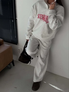 Close-up of red letter embroidery on light grey zip-up sweatshirt and tracksuit set