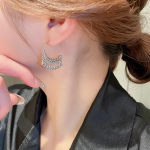 Close-up of silver C-shaped metal tassel earrings featuring delicate water drop pendants