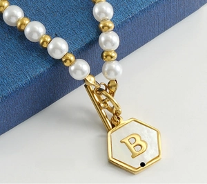 Vue macro du collier en acier inoxydable avec perles et pendentif en nacre avec lettre B