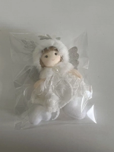 Close-up of a white plush angel ornament with silver sequins and lace dress in packaging