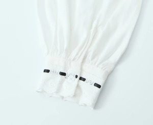 Vue détaillée du poignet de chemise blanc avec ruban noir et bordure en dentelle