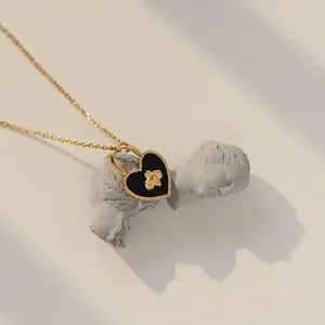 Golden necklace with black heart locket and bee charm on vintage plaster bust