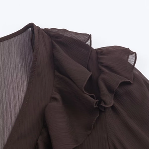 Macro detail of dark brown pleated chiffon dress with layered ruffles and V-neckline