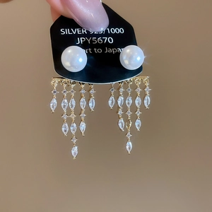 Detailed macro view of 14K gold plated tassel earrings with pearls and marquise zircons