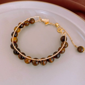 Detail of tiger eye bead bracelet with handmade gold wire wrapping and lobster clasp