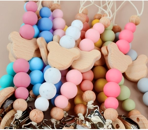 Detail of colorful silicone beads and wooden bear pacifier clips for babies