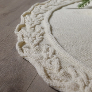 Knitted Christmas tree skirt in cream white with aran cable patterns on wooden floor