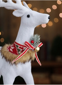 Close-up of white flocked Christmas reindeer with red bow, bell and pine needle detail