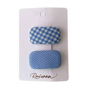 Set of two pastel blue plaid and textured fabric square hair clips on display card