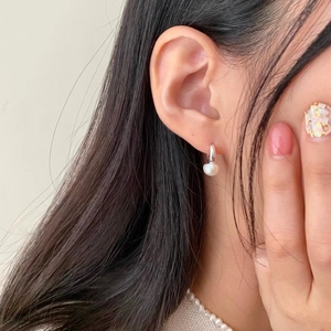 Close-up of a sterling silver pearl drop earring worn on a woman's earlobe