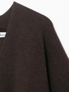 Detail of chocolate knit poncho fabric texture and shoulder seams with MWOMAN brand tag