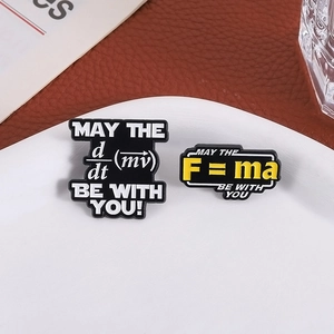 Enamel pins featuring physics formulas F=ma and derivative momentum on leather surface
