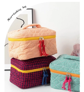 Close-up of three quilted fabric cosmetic bags with colorful patterns and handles