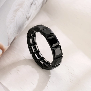 Close-up of geometric black faceted stone stretch bracelet with glossy reflective surface