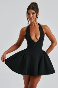 Detail view of deep V-neckline and side pleated hem on elegant black mini dress