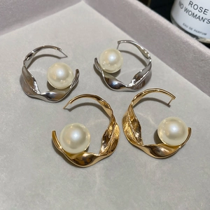 Primo piano di orecchini a cerchio intrecciati con grandi perle in oro e argento.