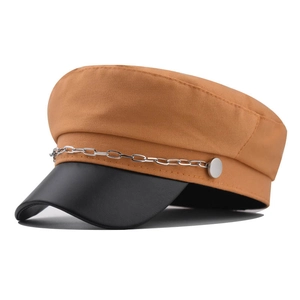 Détail de casquette gavroche orange avec visière en similicuir noir et chaîne argentée