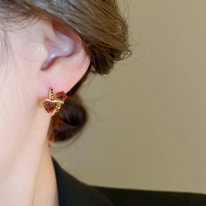 Close-up of model wearing gold twisted hoop earrings with amber square cubic zirconia