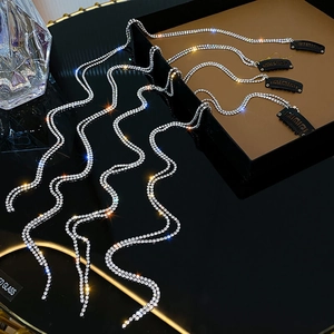 Detail shot of shimmering rhinestone chains with black clip on dark reflective surface