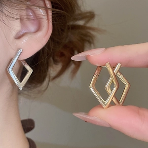 Detail showing geometric rhombic earrings in polished gold and silver metal finishes