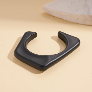 Close-up of a matte black geometric open cuff bracelet with an avant-garde industrial design