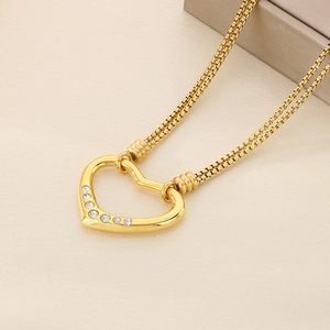 Close-up of golden hollow heart necklace featuring five white zircons on double chains