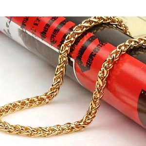 Close-up of golden stainless steel keel chain necklace over a red decorative surface