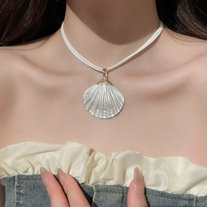 Close-up of a white painted shell pendant necklace with metal clasp on a leather cord