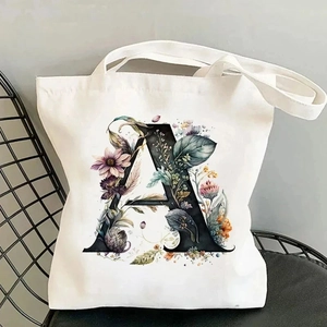 Detail of white canvas tote bag with black letter A and colorful floral pattern illustration