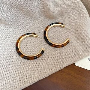 Detailed close-up of C-shape resin hoop earrings with vintage tortoiseshell and gold finish