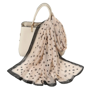 Elegant lightweight chiffon scarf with floral pattern draped on a cream handbag