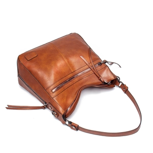 Detail of caramel faux leather shoulder bag with decorative metal zippers and long pullers