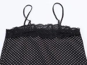 Detail of black polka dot camisole featuring floral lace trim and adjustable thin straps