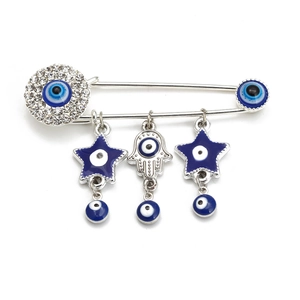 Macro detail of silver Hamsa hand brooch with blue Evil Eye charms and rhinestones