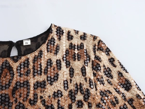 Gros plan sur les paillettes léopard et les coutures en maille sur l'encolure ronde
